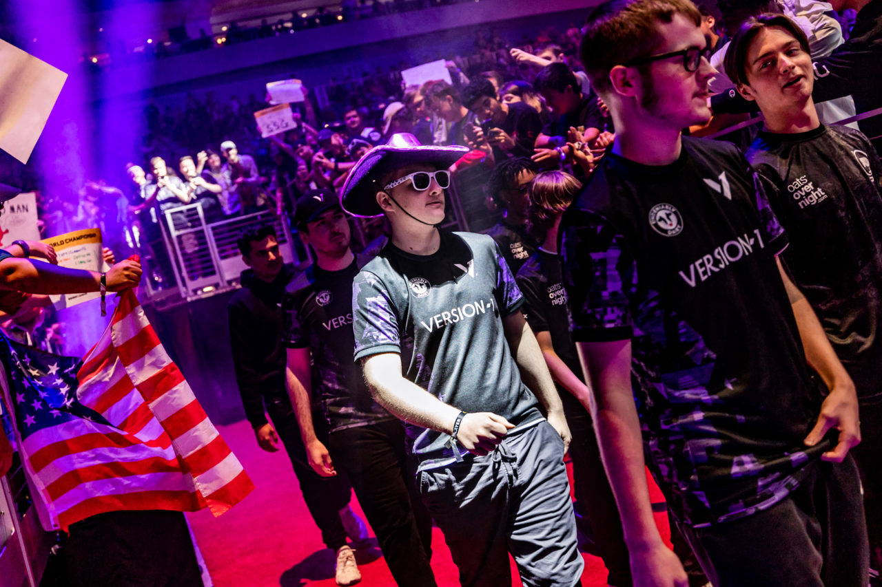 Version1 Rocket League has advanced to the playoffs at RLCS Worlds. In this image, Beast, Comm, Torment, and Fireburner are entering the arena. Comm is wearing a cowboy hat.