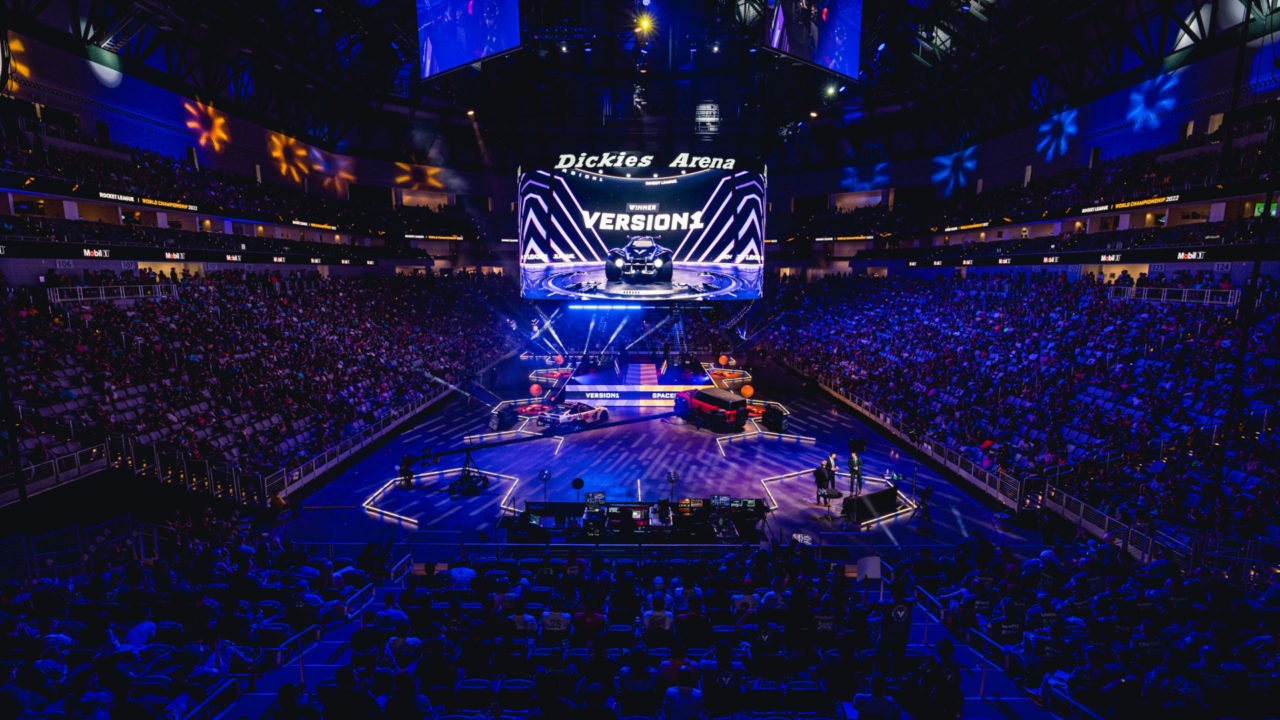 The screen at Dickies Arena during RLCS Worlds displays a large "Version1" logo as Version1 Rocket League begins to enter the tournament venue.